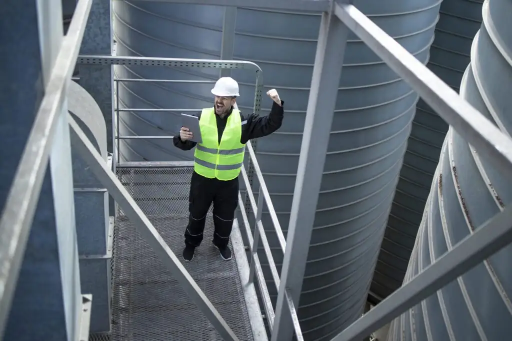 Inspecteur met veiligheidsvest tussen industriële installaties